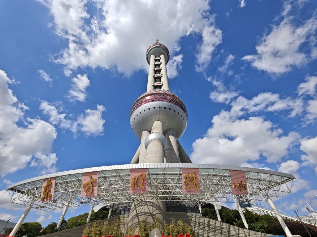 東方明珠塔仰拍：蔚藍天空下標誌性粉紫色球體與入口區域