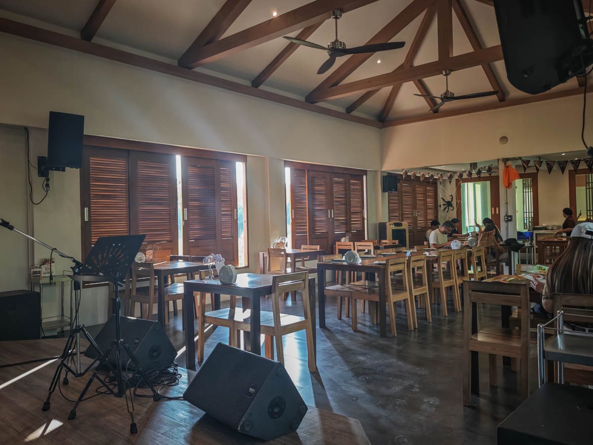 CHOM Cafe 室內用餐區,木桁架屋頂、吊扇與木百葉窗